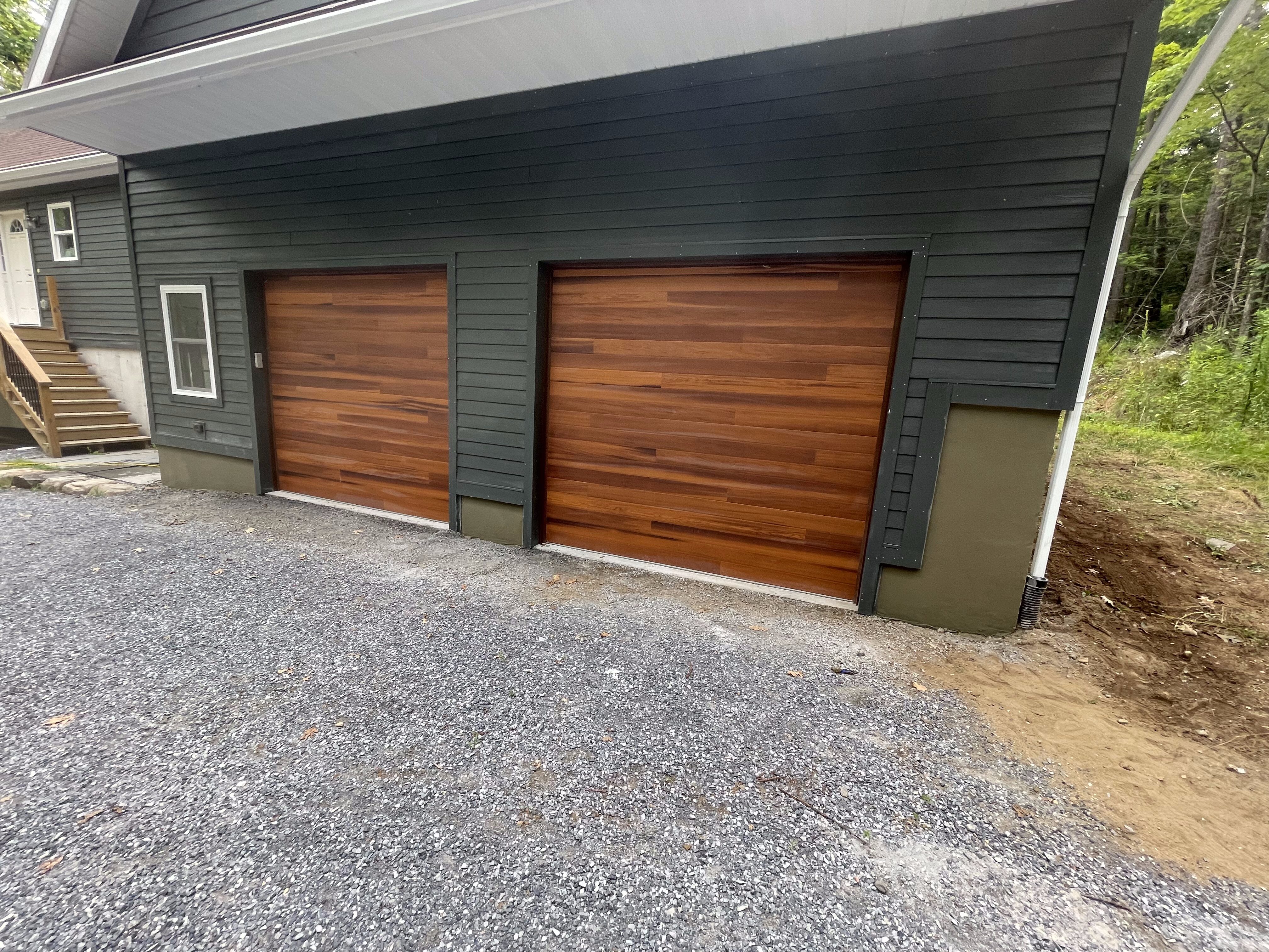IMG_0628 Two modern wooden garage doors set in a dark gray residential property with clean, precise craftsmanship, showcasing Excelsior Property Management’s commitment to quality and attention to detail in property maintenance and development.
